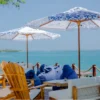 Wooden sun chairs and umbrellas facing the sea at Capri Beach Club