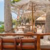 Shaded wooden deck with loungers among palm trees at Ibbiza Island Beach Club