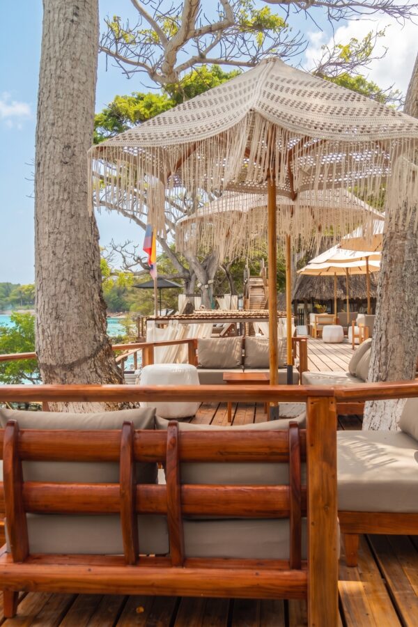 Shaded wooden deck with loungers among palm trees at Ibbiza Island Beach Club