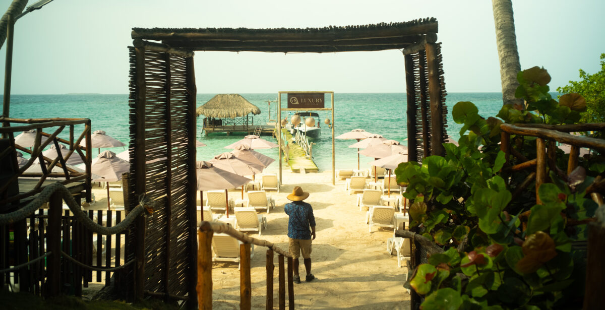 Rustic wooden entrance arch leading to the beach at Luxury Beach Club
