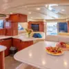 Salon with dining table, kitchen and fruit platter on the Cork Trick yacht